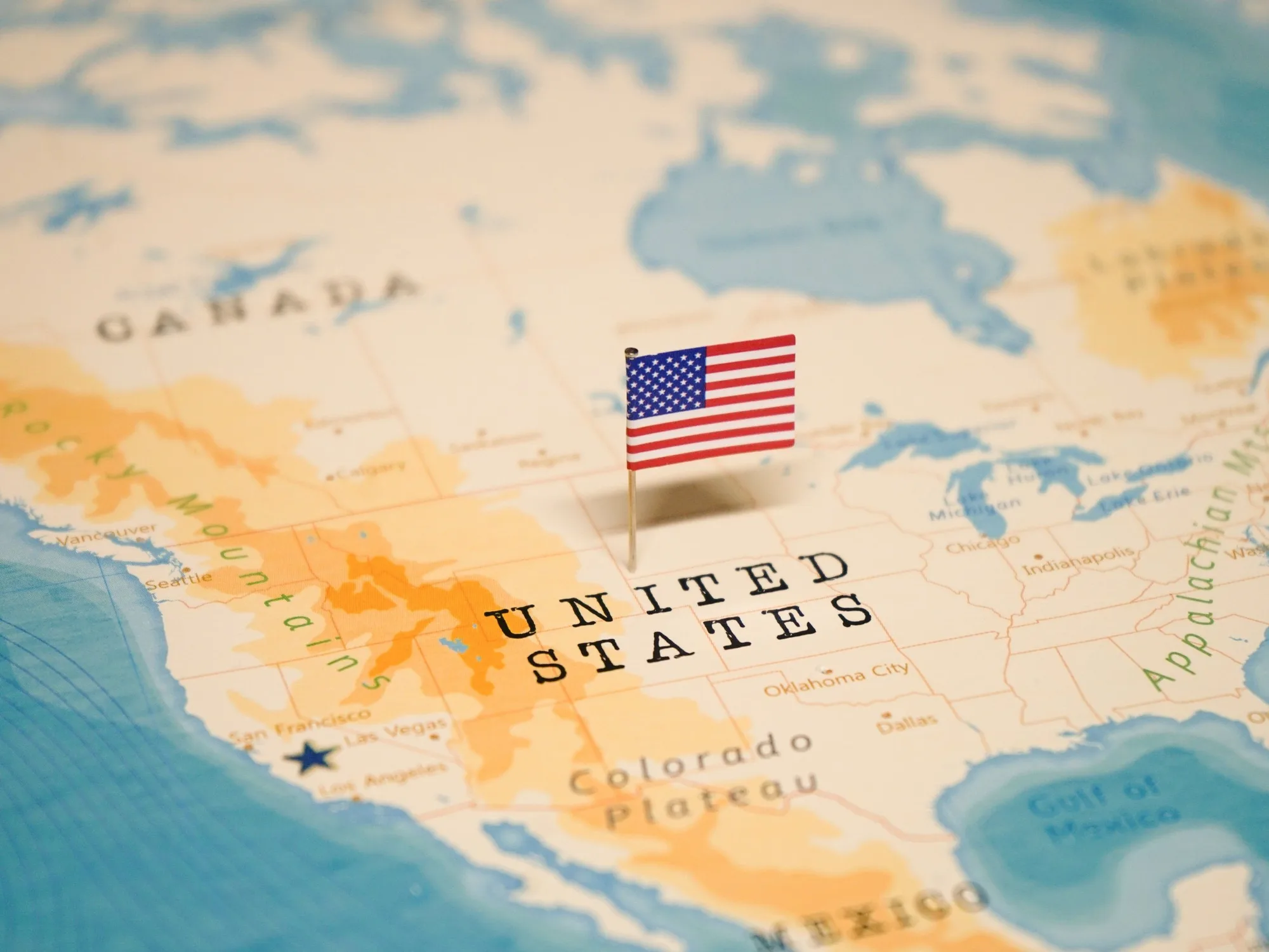 Close-up of a world map with a small American flag pin placed over the United States.